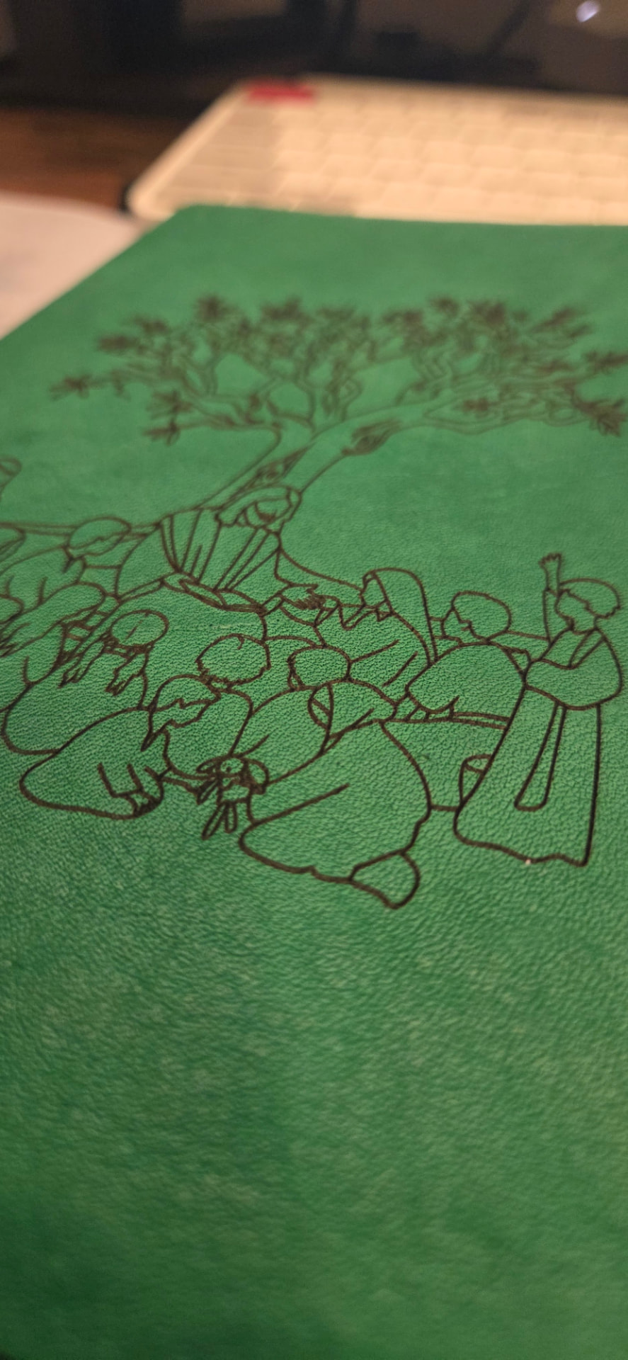Close-up detail of the engraved tree design on green leather